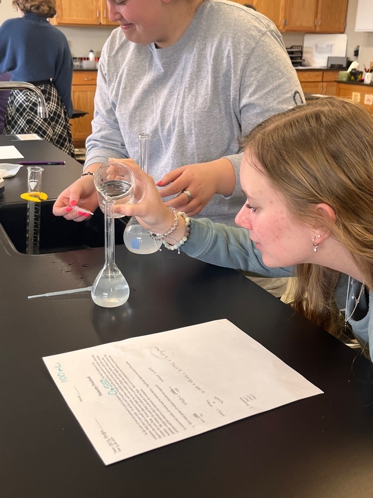 Juniors Carly Vaughn and Makayla Winebaugh perform a lab practical by making a salt solution in Chemistry II class. Photo by M. Paxton
